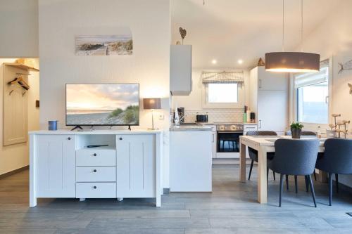 a kitchen and dining room with a white cabinet and a table at Wattkueken in Simonsberg