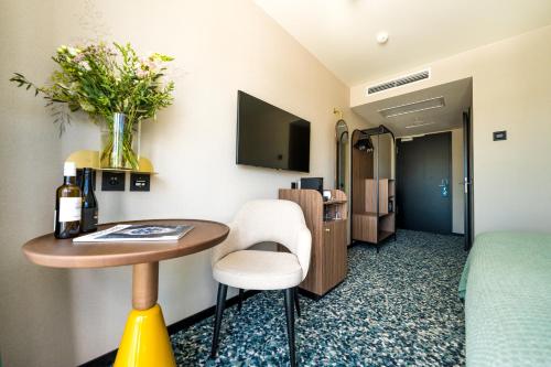 a hotel room with a table with a vase of flowers at Hotel D Bulle - La Gruyère in Bulle