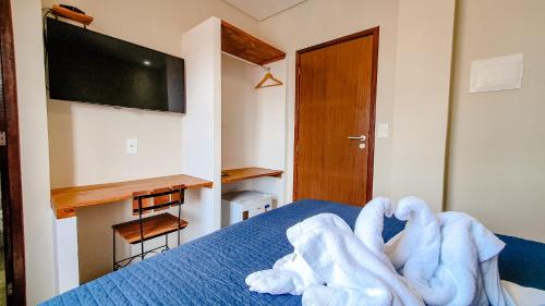 a bedroom with a bed with blue sheets and a flat screen tv at Pousada Sete Mares in Maragogi