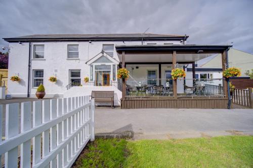 a white house with a porch and a white fence at Entire Venue Hire with 8 Bedroom Accommodation - Your Own Pub Experience in Swansea