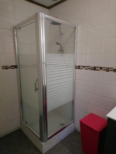 a shower stall in a bathroom with a red stool at Charmant bungalow F3 sur la plage de petite anse, Bouillante in Bouillante