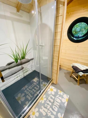 une douche avec une porte vitrée dans une pièce dans l'établissement LeJardinZenduQuistillic, à Saint-Guen