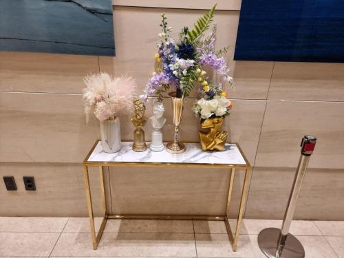 a table with vases and flowers on it at Hotel bridge Seogwipo in Seogwipo
