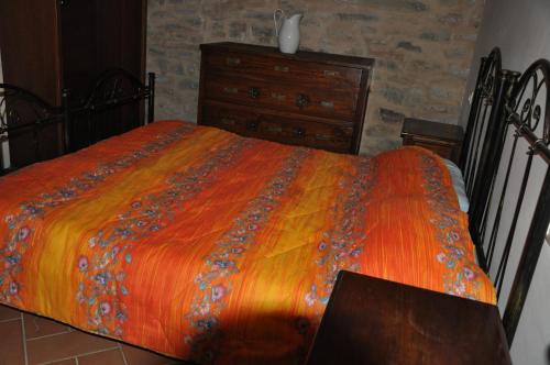 a bedroom with a bed with an orange blanket and a dresser at Farmstay Agriturismo La Fonte in Belforte del Chienti