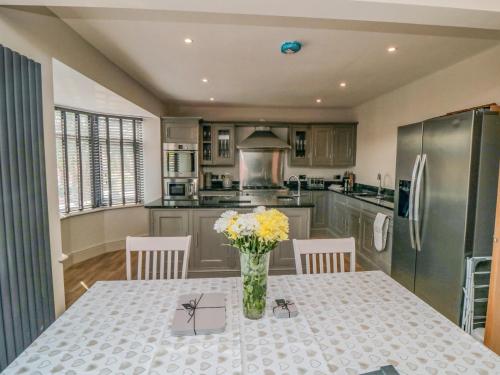 a kitchen with a table with a vase of flowers on it at Nightingales in Bridlington