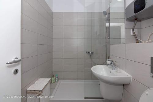 Un baño blanco con lavabo y ducha. en De Silva, en Mamaia