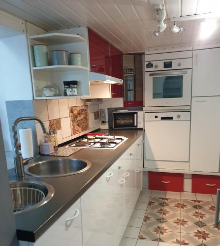 - une cuisine avec des placards rouges et blancs et un évier dans l'établissement Maison bord de Marne 8min disneyland et val d'Europe, à Chalifert