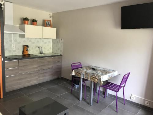 - une cuisine avec une table et des chaises violettes dans la chambre dans l'établissement Sol-y-Days Escale Port, Agréable studio au RDC, résidence avec piscine entre la plage nord et Port Camargue, au Grau-du-Roi