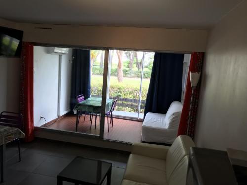 un salon avec un canapé, une table et une fenêtre dans l'établissement Sol-y-Days Escale Port, Agréable studio au RDC, résidence avec piscine entre la plage nord et Port Camargue, au Grau-du-Roi