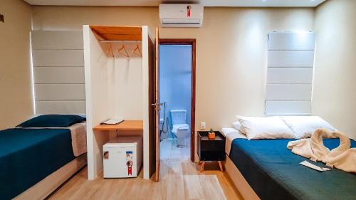 a bedroom with two beds and a desk and a door at Pousada Sete Mares in Maragogi