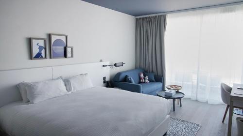 a bedroom with a white bed and a blue chair at Hotel Indigo Cagnes-sur-Mer by IHG in Cagnes-sur-Mer