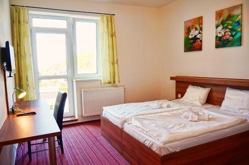 um quarto com uma cama, uma secretária e uma janela em Restaurace a penzion Zděná Bouda em Hradec Králové