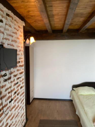 een slaapkamer met een bakstenen muur en een tv aan een muur bij Александрова вила 2 in Zlatograd