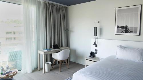a hotel room with a bed and a desk with a computer at Hotel Indigo Cagnes-sur-Mer by IHG in Cagnes-sur-Mer