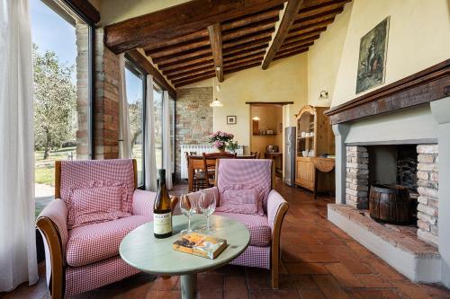 een patio met 2 stoelen en een tafel met een fles wijn bij Agriturismo Montalbino in Montespertoli