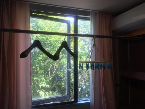a window with a hanger in front of a curtain at Narita Airport Samurai Hostel in Kujukuri