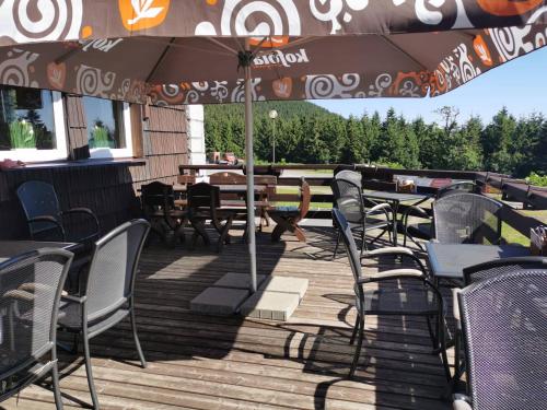 an outdoor patio with tables and chairs and an umbrella at Hotel Červenohorské sedlo in Loučná nad Desnou
