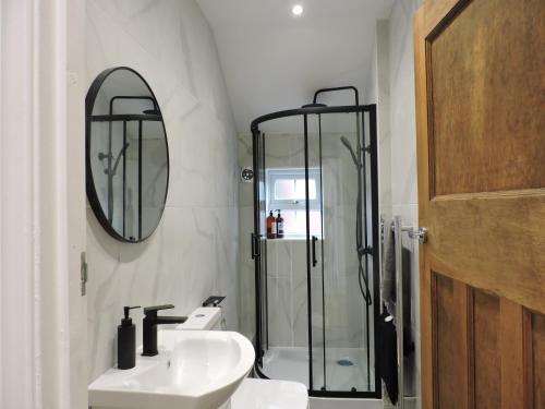 a bathroom with a shower and a sink and a mirror at Bespoke Luxury Serviced Apartment in Macclesfield