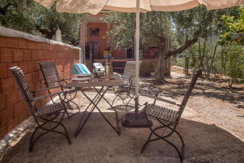 a table and chairs under an umbrella on a patio at Little country hut 'Mikri Eleni' in Akrogiali