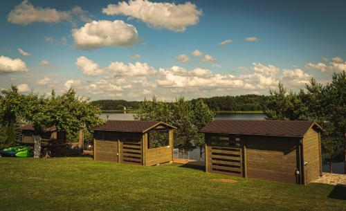 two small buildings in a yard with a lake at Kupiškėnų Starkėnas in Palėvenėlė