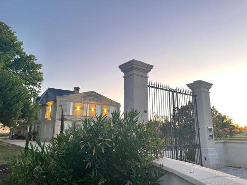 une maison avec un portail et un bush devant elle dans l'établissement Château de Neyran chambre d'hôtes & Spa, à Soulac-sur-Mer
