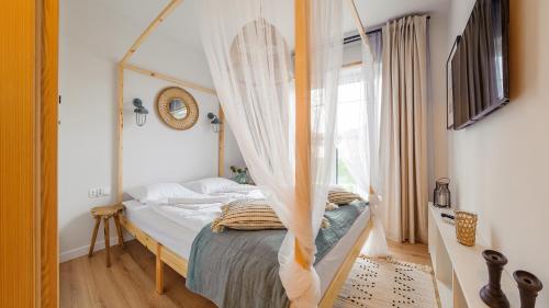 a bedroom with a canopy bed with a window at Apartamenty Sun & Snow Port Krynica in Krynica Morska