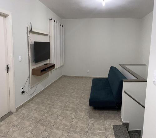 a living room with a blue chair and a television at Apartamento a 200m da Praia do Morro com Wifi in Guarapari