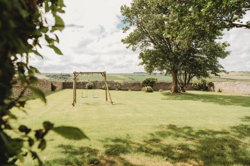 a swing set in a field with a tree at The Herdsman's House in Thurso