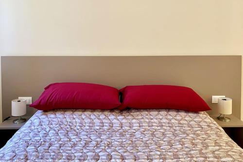 a bed with two red pillows in a bedroom at Residenza SubitoSanto - Appartamento 4A "Mantegna" in Padova