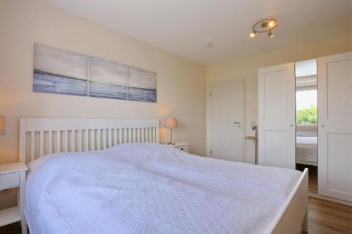 a bedroom with a white bed and a painting on the wall at Haffblick Wohnung 41 in Boltenhagen