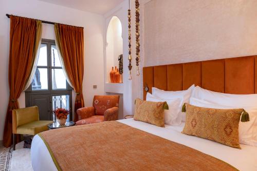 um quarto de hotel com uma cama grande e uma cadeira em Riad LAZ Mimoun & Spa em Marrakech