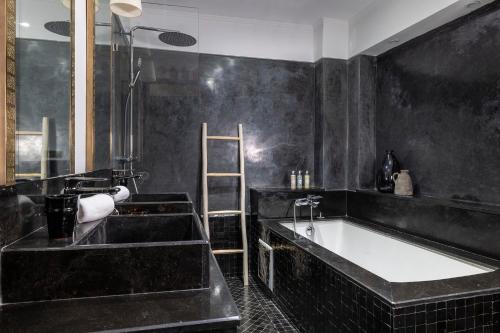 a black bathroom with a tub and a sink at Riad LAZ Mimoun & Spa in Marrakesh