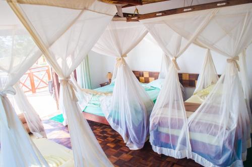 a bedroom with four beds with mosquito nets at RELAIS DU KIRINDY in Kirindy