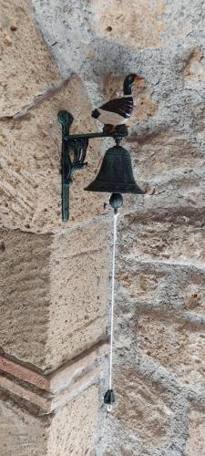 a bird sitting on a bell on a stone wall at LA CHASCONA DI FARNESE casa di tufo nel borgo in Farnese