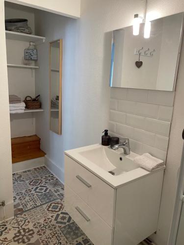 une salle de bain blanche avec un lavabo et un miroir dans l'établissement Location La Ferté, calme et proximité centre ville classé 3 Étoiles, à Lons-le-Saunier