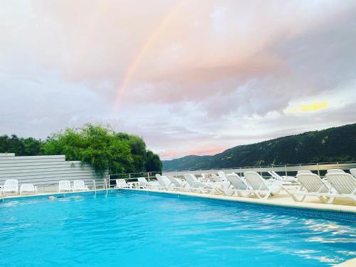 ein Pool mit Stühlen und ein Regenbogen am Himmel in der Unterkunft Pensiunea Onyx in Eşelniţa