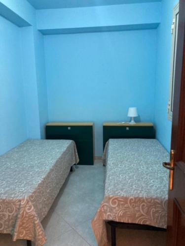een kamer met 2 bedden en een blauwe muur bij Casa Triscele Bis in Ispica
