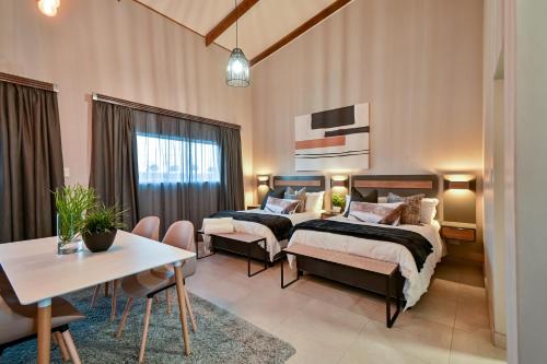 two beds in a room with a table and chairs at Summer PALACE Guesthouse in Bloemfontein