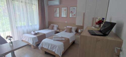 een kamer met 2 bedden en een laptop op een bureau bij Forest Apartments in Bitola