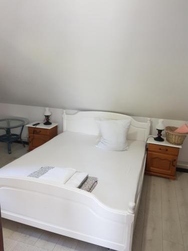 a large white bed in a room with two tables at Pensiunea Daria Putna in Putna