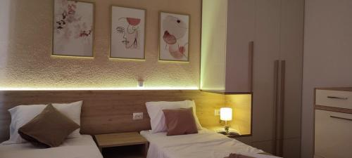 a bedroom with two beds and two pictures on the wall at Forest Apartments in Bitola