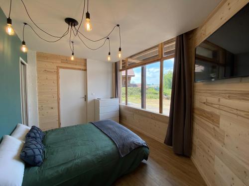 a bedroom with a bed and a large window at La Parenthèse du Dahu Gîte de 6 pers in Métabief