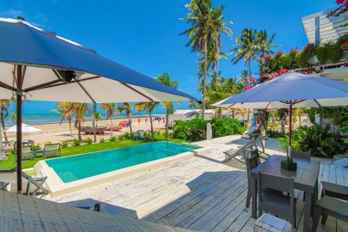 einen Pool mit Sonnenschirmen und einen Strand in der Unterkunft Depraia Apartments in Icaraí