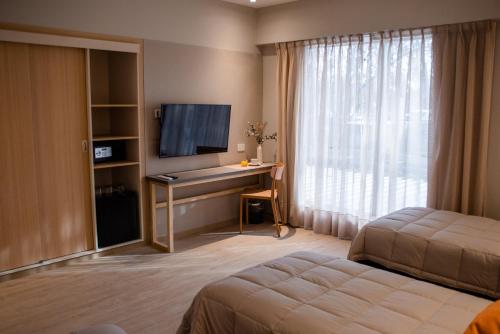 a hotel room with a bed and a desk with a television at Gran Hotel Dakar in Mendoza