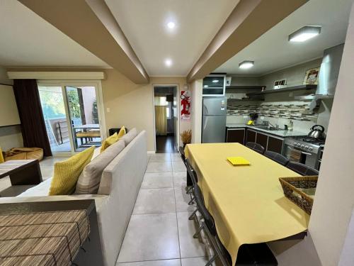 LA CASA DEL LAGO TANDIL في تانديل: مطبخ وغرفة معيشة مع طاولة وأريكة