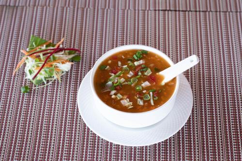 a bowl of soup on a plate with a salad at HOTEL JS SOUVENIR in Dehradun