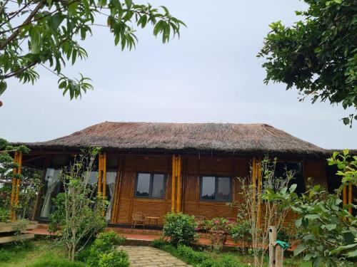 a wooden house with a thatched roof at ByVe Garden in Hanoi