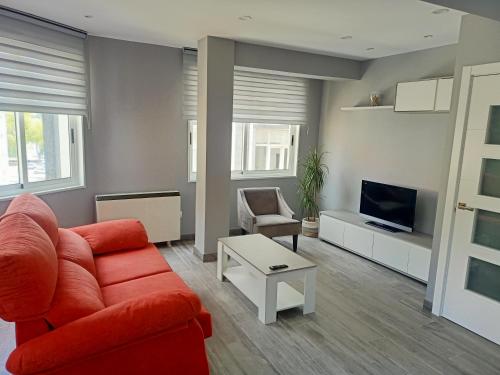 a living room with a red couch and a tv at O Abeiro do Eume in Puentedeume