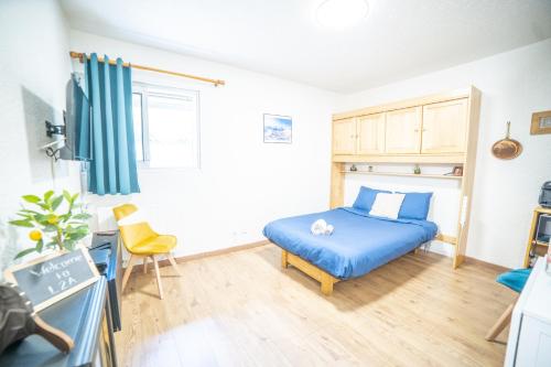 - une chambre avec un lit bleu et un bureau dans l'établissement Les 2 Alpes - PIED DES PISTES - PLEIN CENTRE DE LA STATION au calme, à Les Deux Alpes