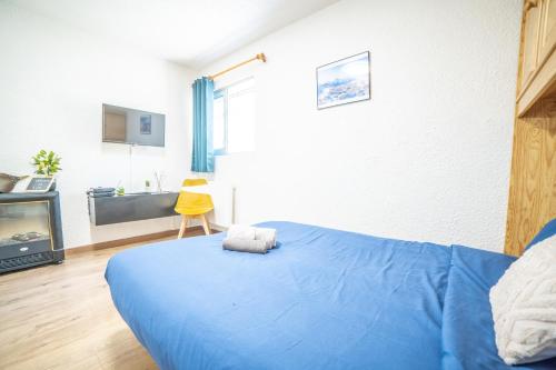 - une chambre avec un lit bleu et une télévision dans l'établissement Les 2 Alpes - PIED DES PISTES - PLEIN CENTRE DE LA STATION au calme, à Les Deux Alpes